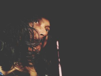 Close-up portrait of girl against black background