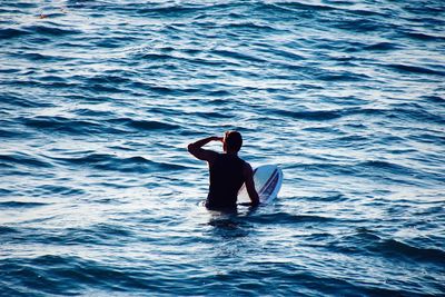 Rear view of man with surfboard in sea