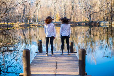 Rear view of women standing by lake