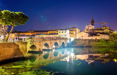 Arch bridge over river against buildings in city