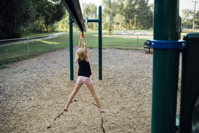 Rear view of girl zip lining at playground