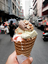 Hand holding ice cream cone on street