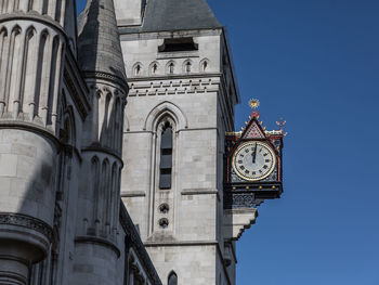 Shiny and shining golden clock, detail of the royal courts of justice facade in london.