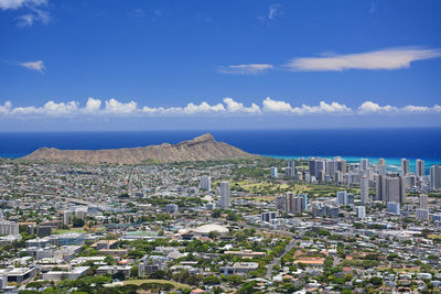 High angle view overlooking honolulu buildings against blue sky with diamond head in background. 