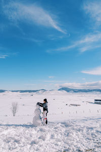 Woman skiing on snow covered field against sky