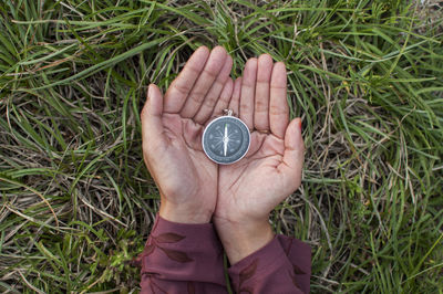 Close-up of woman holding navigational compass on field