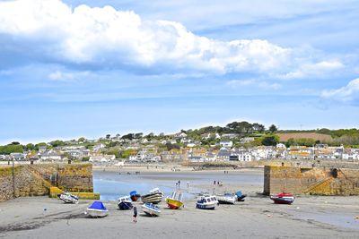 Boats on beach by sea against sky in city