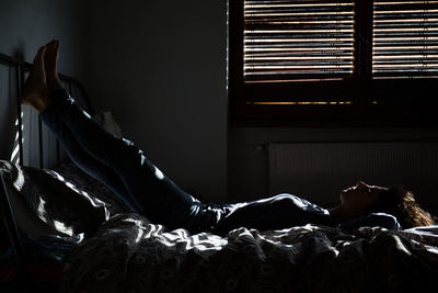 Full length of young woman lying on bed