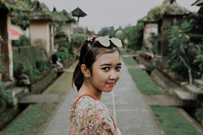 Portrait of young woman standing on footpath