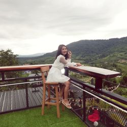 Full length of woman standing on railing against sky