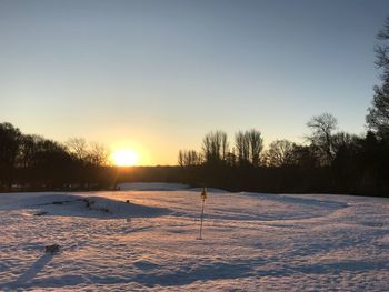 Scenic view of snow covered field against clear sky during sunset