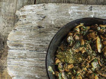 Directly above shot of fried mushrooms in skillet on wooden table