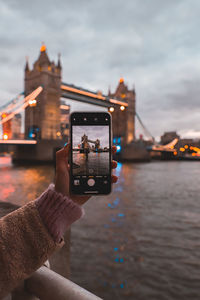 Man photographing on mobile phone against sky