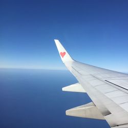 Airplane wing against clear blue sky