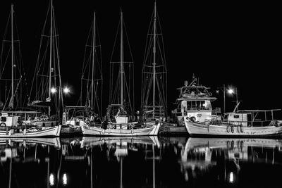 Sailboats moored in harbor at night