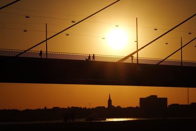 Silhouette bridge over river against sky during sunset