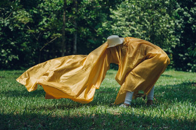 Person holding yellow fabric while standing on field