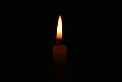 Close-up of lit candle in dark room