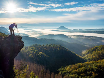 Photographer on mountain witch through viewfinder. morning landscape from top of the mountain