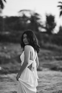 Young woman looking away while standing at beach