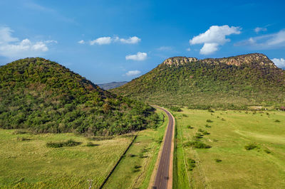 Scenic view of road amidst field against sky