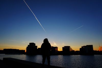 Rear view of silhouette man standing in city against sky