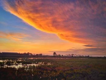 Scenic view of dramatic sky over land during sunset