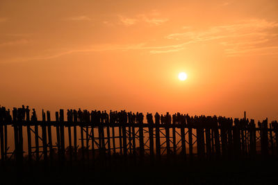 Silhouette people on landscape against sky during sunset
