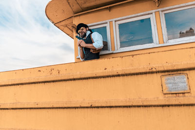 Low angle portrait of man standing against wall