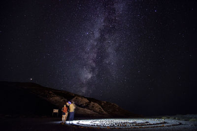 Full length of woman standing on field against sky at night