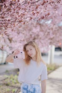 Portrait of young woman standing against trees