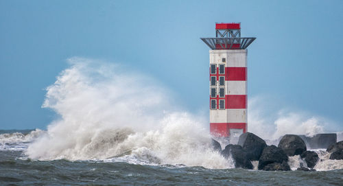 Lighthouse by sea against sky