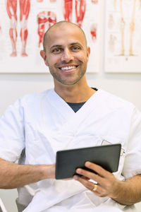 Portrait of happy doctor holding digital tablet in orthopedic clinic