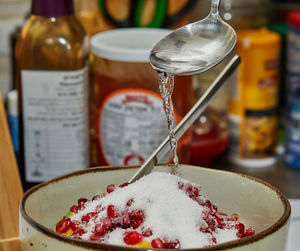 Chef adds syrup to the fruit salad at home in the kitchen