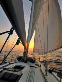 Sailboat sailing on sea against sky during sunset