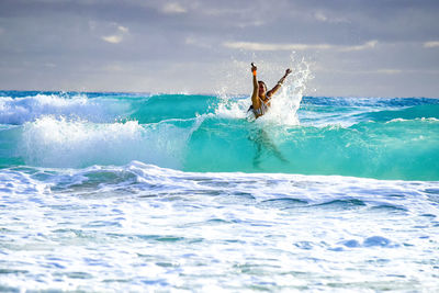 Rear view of man surfing in sea