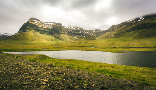 Scenic view of lake and mountains against cloudy sky