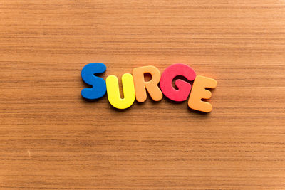 High angle view of colorful surge text on wooden table