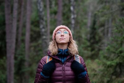 Portrait of a woman looking up at the sky in a forest in winter