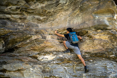 Young boy climbing the rocks wearing a backpack.