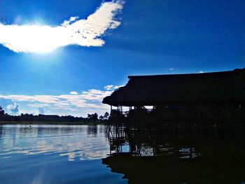 Silhouette built structure by lake against sky