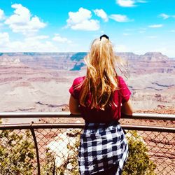 Rear view of woman standing on landscape against sky