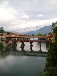 Bridge over river in city against sky