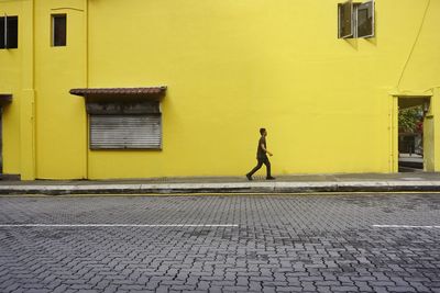 Side view of a person standing against yellow wall