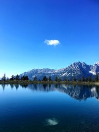 Scenic view of lake by mountains against blue sky