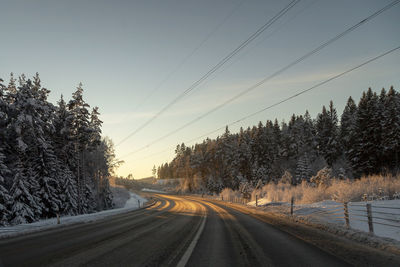 Road amidst trees against clear sky