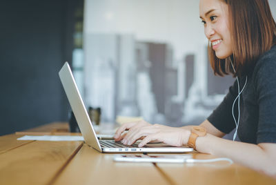 Woman using laptop while sitting on table