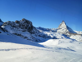 Scenic view of snowcapped mountains against clear blue sky