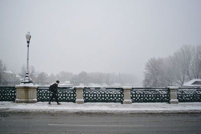 Man walking on sidewalk in city during winter