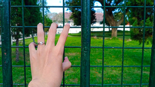 Close-up of human hand on metal fence